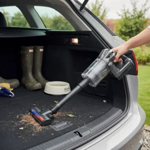 A handheld vacuum being used to clean the boot of an estate car, with wellington boots in the background.