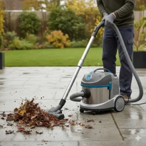 Clearing wet leaves and garden debris from a stone patio using a versatile outdoor vacuum.