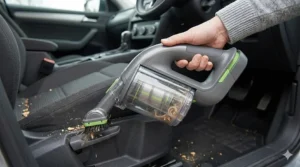 Using a Gtech handheld vacuum cleaner to hoover car seats and footwells for a professional finish.