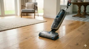 A cordless hard floor cleaner being used on polished light oak hardwood flooring in a living room.