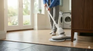 Alt text for image 6: A detailed photorealistic photograph from a low angle, showing the flexible swivel head of the electric spin mop maneuvering easily under a low utility sideboard on a clean light oak floor in a modern UK home.
