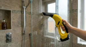 Using a rechargeable window vacuum to remove condensation from a bathroom shower screen.