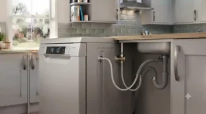 Plumber connecting the water supply hose to a budget freestanding dishwasher during kitchen setup