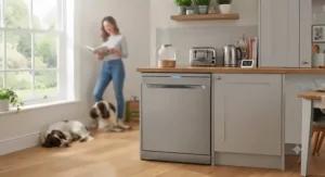 A peaceful, open-plan British kitchen with a quiet freestanding dishwasher operating in the background.