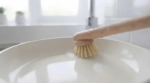 Angled cleaning brush head reaching into the tight corners of a deep saucepan.