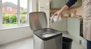 A layer of baking soda sprinkled at the bottom of a clean kitchen bin beneath the bin liner.