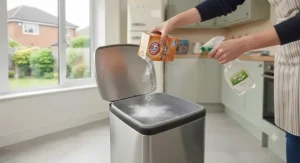 Sprinkling baking soda and spraying white vinegar inside a smelly kitchen bin to neutralise odours.