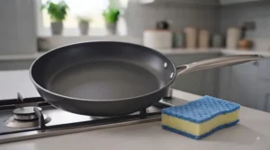 Rinsing a non-scratch sponge under a kitchen tap to remove food debris after cleaning a pan.