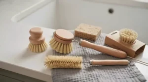 Wooden washing-up brush removing food residue from the bottom of a stainless steel saucepan.
