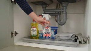 A collection of kitchen cleaning products and kitchen degreasers safely stored under a sink cupboard.